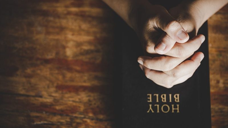 Praying hands over the Bible
